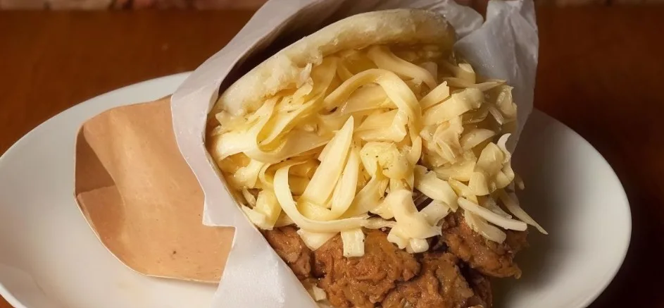 Arepa venezolana rellena de carne mechada y abundante queso rallado